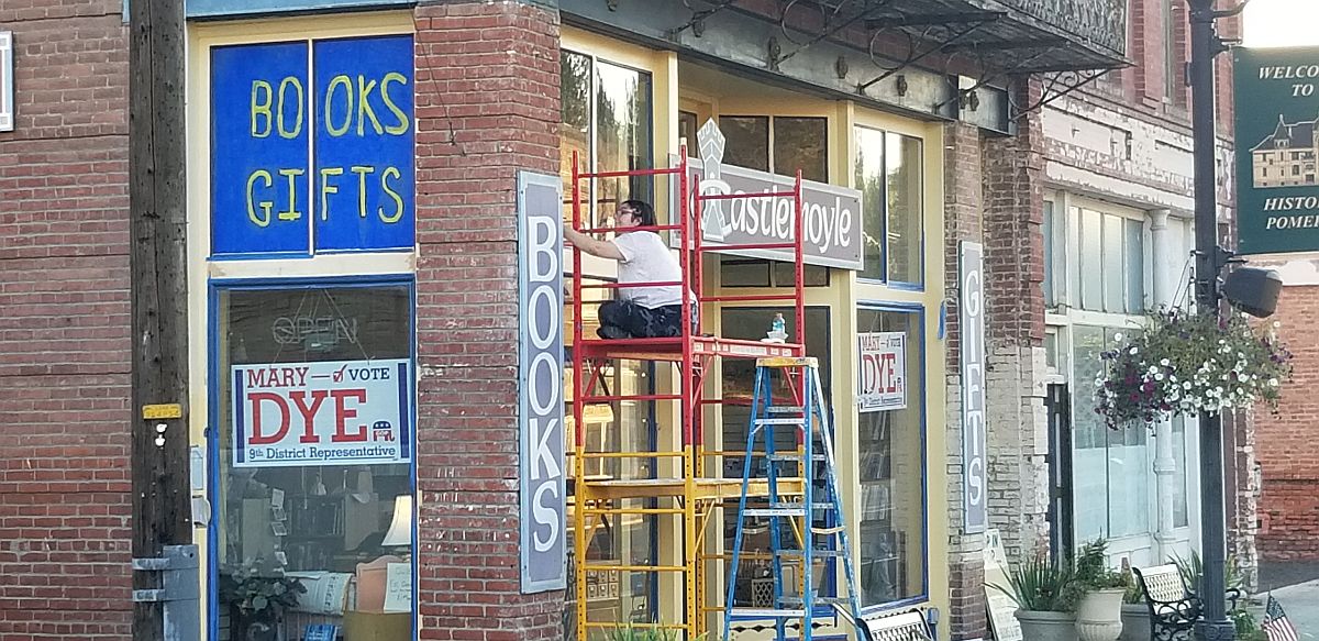 2022, painting the window trim of Castlemoyle Books, Pomeroy WA